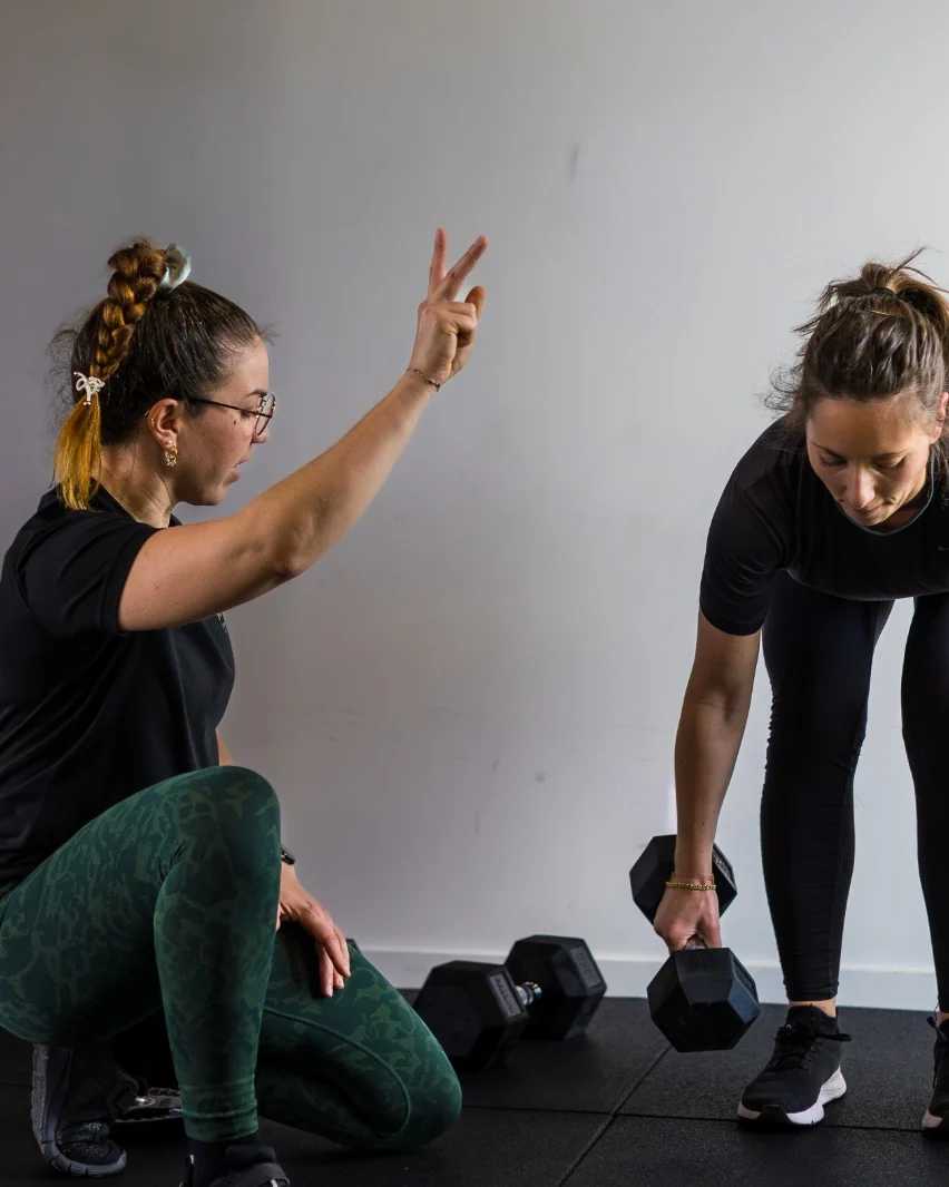 Une coach CORPO encourage une collaboratrice au soulevé de terre