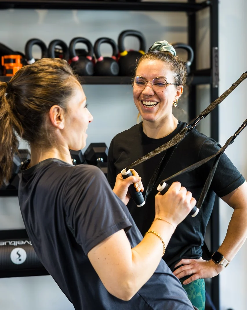 Deux collaboratrices échangent en riant pendant un exercice de sangles