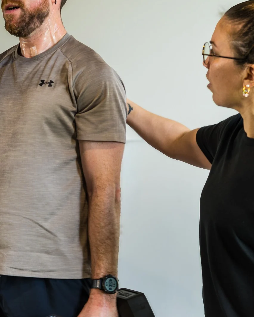 Une coach CORPO corrige la posture d'un collaborateur, haltères en main